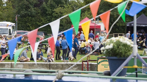 Visitors on the bank watching decorated boats along the river